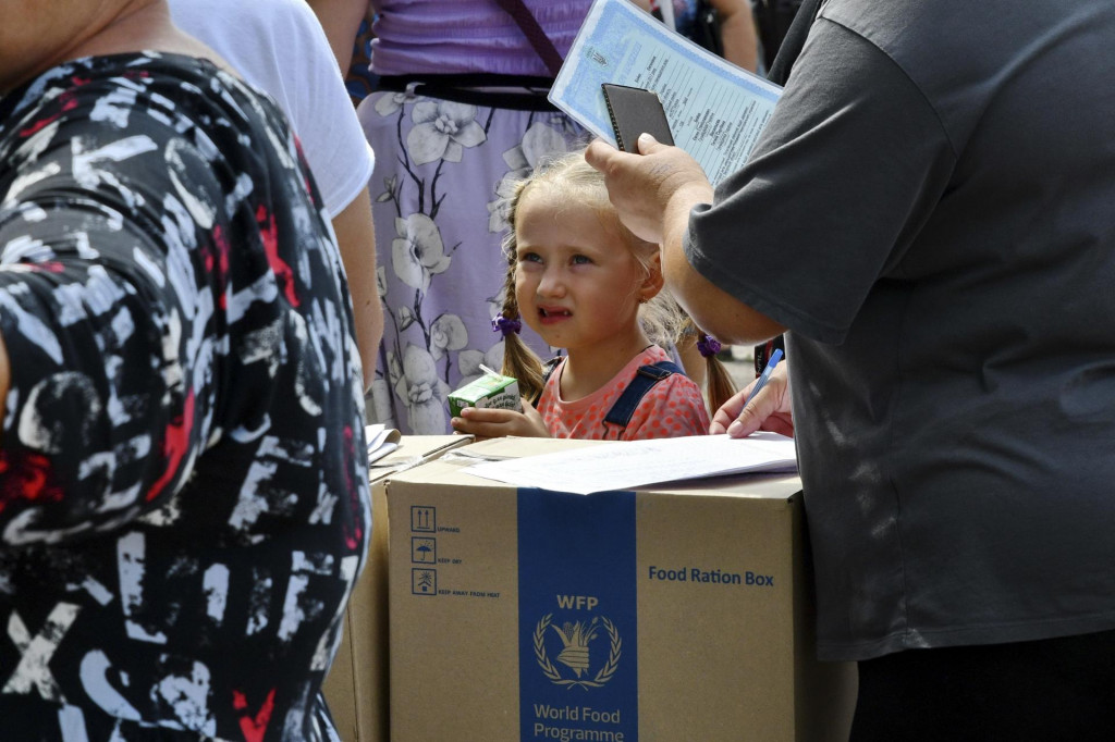 Ľudia stoja v rade a čakajú na prídel potravín na mieste distribúcie humanitárnej pomoci v meste Záporožie. FOTO: TASR/AP