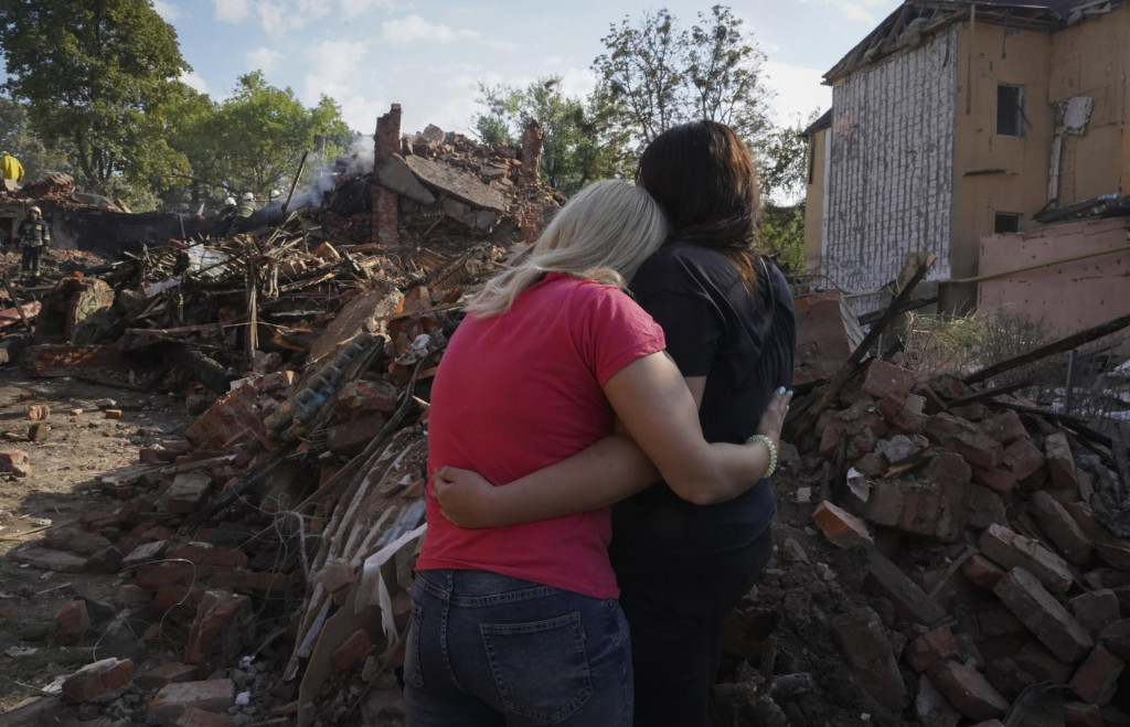 Ukrajinské ženy sa objímajú pred budovou zničenou pri raketovom útoku v Charkove. FOTO: TASR/AP