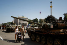 

Pár s dieťaťom navštívi výstavu zničených ruských vojenských vozidiel a zbraní. FOTO: Reuters