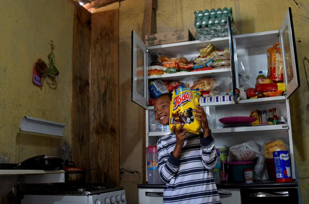 Miguel Felipe Barros de Oliveira, ktorý zavolal na políciu, že jeho rodina je hladná, vystavuje jedlo darované darcami v Santa Luzii v Brazílii. FOTO: Reuters