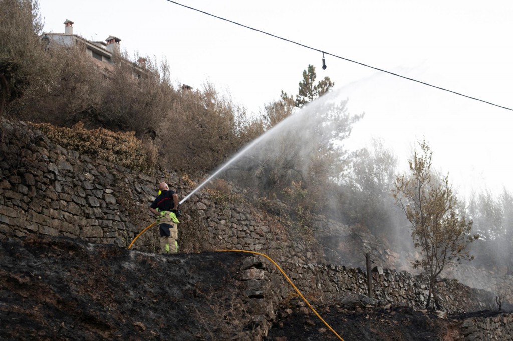 Hasiči striekajú vodu zo spálenej cesty v regióne Valencia, v španielskom Bejis. FOTO: Reuters