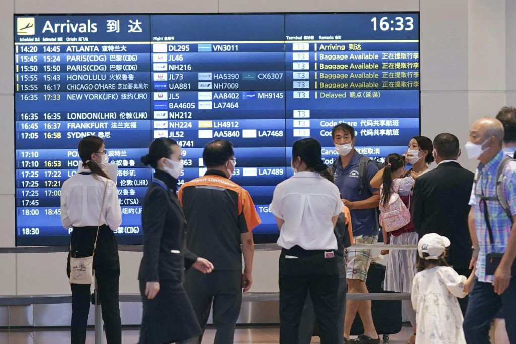 Ľudia majú na tvári respirátori v príletovej hale letiska Haneda v Tokiu. FOTO: TASR/AP
