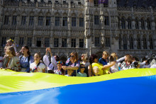 Ľudia nesú obrovskú ukrajinskú vlajku na námestí Grand Place v Belgicku. FOTO: Reuters