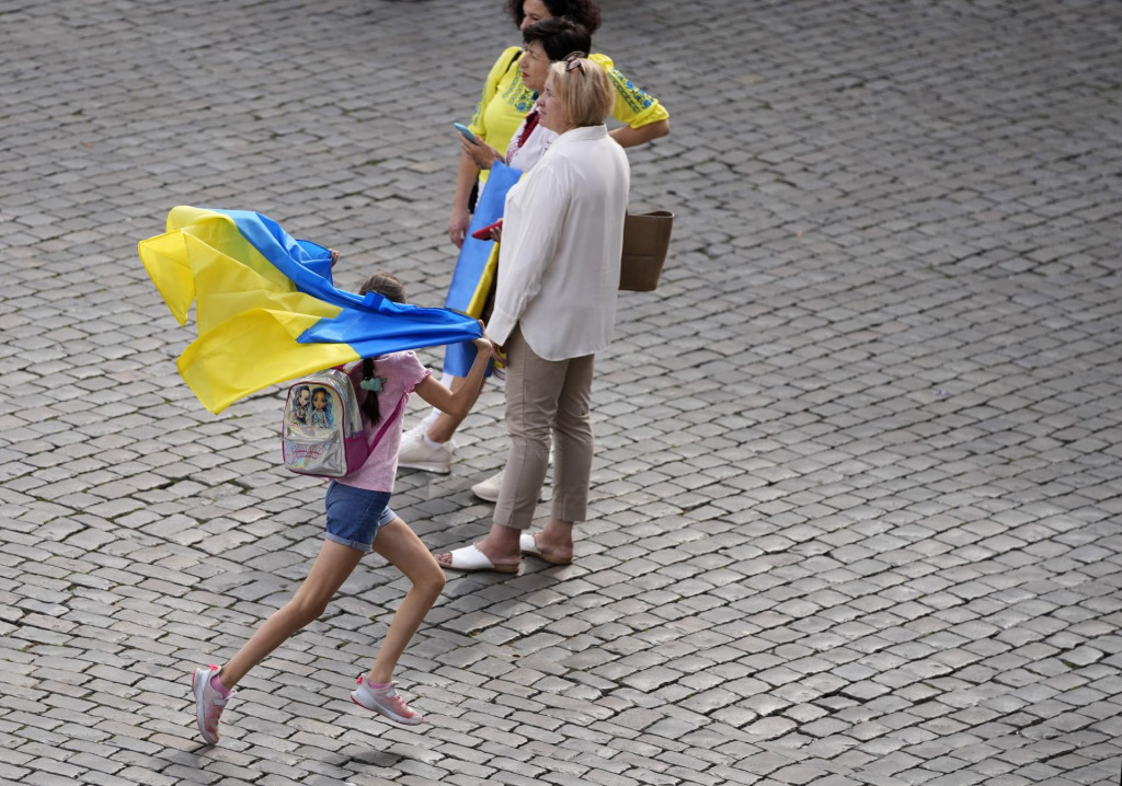 Dievča uteká s ukrajinskou zástavou počas osláv Dňa nezávislosti Ukrajiny. FOTO: TASR/AP