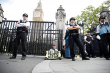 Účastník protestu Extinction Rebellion sedí pred bránami britského parlamentu.