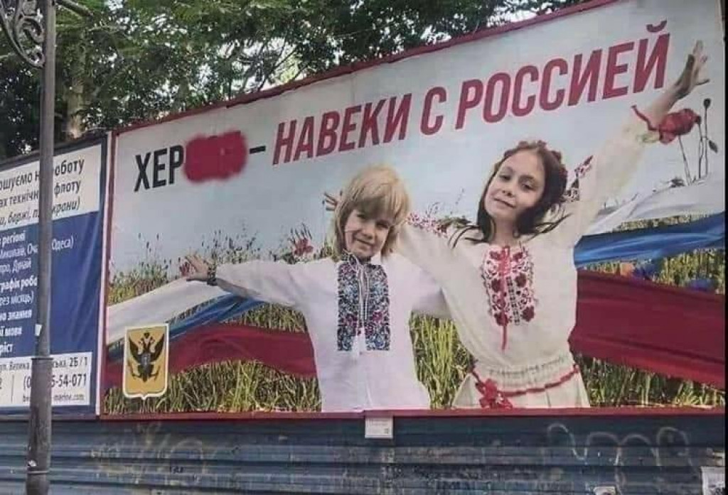 Rusi ukradli fotografiu ukrajinskej fotografky s jej synom a jeho priateľom – a vytvorili z toho ruský propagandistický plagát v okupovanom Chersone. FOTO: Reuters