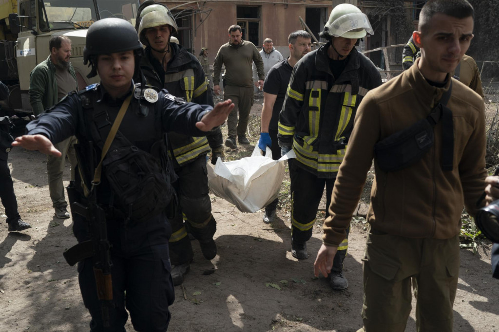 Hasiči vynášajú telo obete zo zničenej obytnej budovy po ruskom raketovom útoku. FOTO: TASR/AP