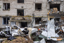 Muži sledujú scénu a fajčia v obytnej budove zničenej útokom. FOTO: Reuters