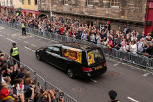 

Ľudia sledujú automobil nesúci rakvu britskej kráľovnej Alžbety na Royal Mile v Edinburghu. FOTO: Reuters