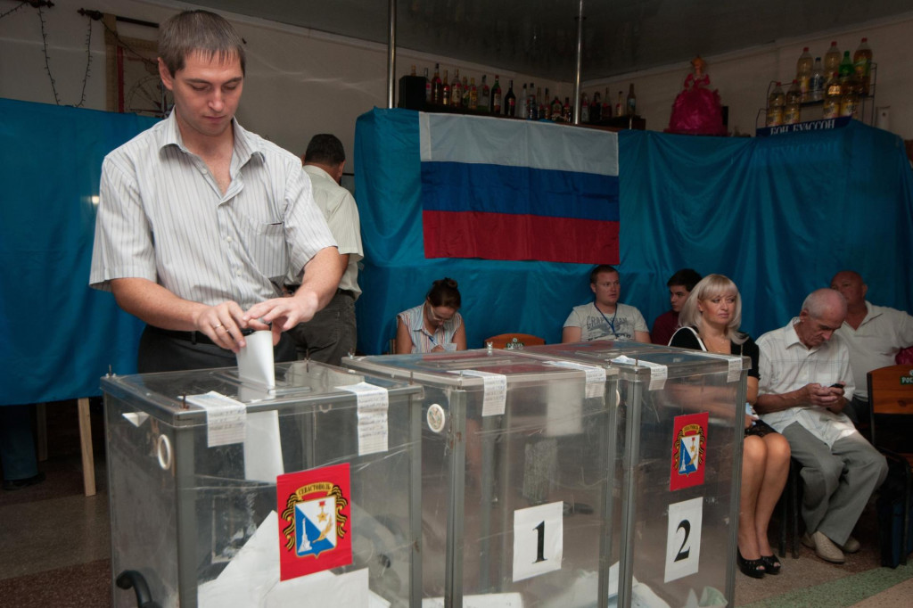 Muž vhadzuje svoje hlasovacie lístky v regionálnych a komunálnych voľbách v Sevestopole. FOTO: TASR/AP