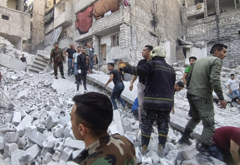 Členovia sýrskej civilnej obrany a bezpečnostných jednotiek pátrajú po obetiach v troskách budovy v sýrskom meste Aleppo. FOTO: TASR/AP