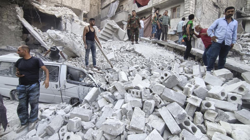 Členovia sýrskej civilnej obrany a obyvatelia mesta pátrajú po obetiach v troskách budovy v sýrskom meste Aleppo. FOTO: TASR/AP