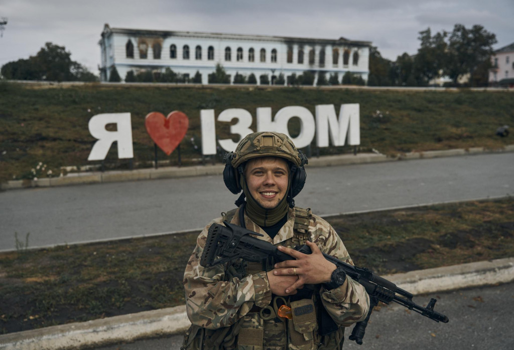 Ukrajinský vojak sa usmieva pred nápisom Milujem Izium. FOTO: TASR/AP