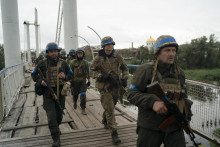 Ukrajinskí vojaci kráčajú cez most v meste Izium. FOTO: TASR/AP
