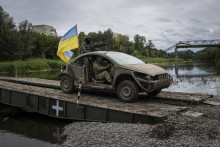 Ukrajinskí výsadkári prechádzajú vozidlom s ukrajinskou vlajkou po pontónovom moste cez rieku Severský Donec v ukrajinskom meste Izium. FOTO: TASR/AP
