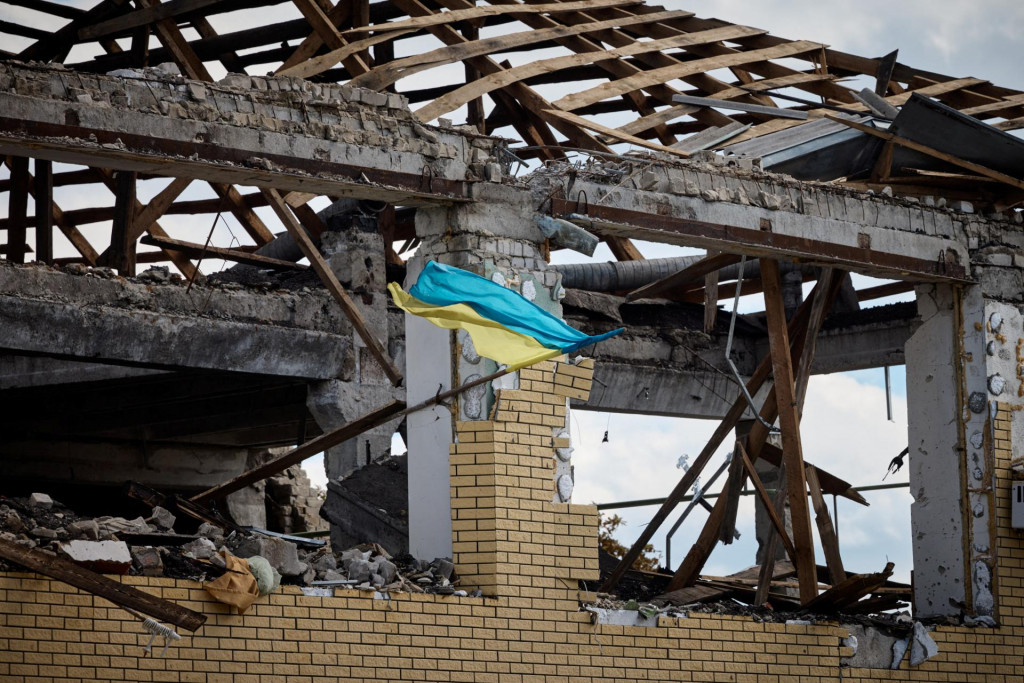 Ukrajinská vlajka na zbombardovanej budove v Kupjansku. FOTO: REUTERS