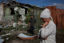 Obyvatelia Ukrajiny stoja pri ich zničenom dome. FOTO: Reuters