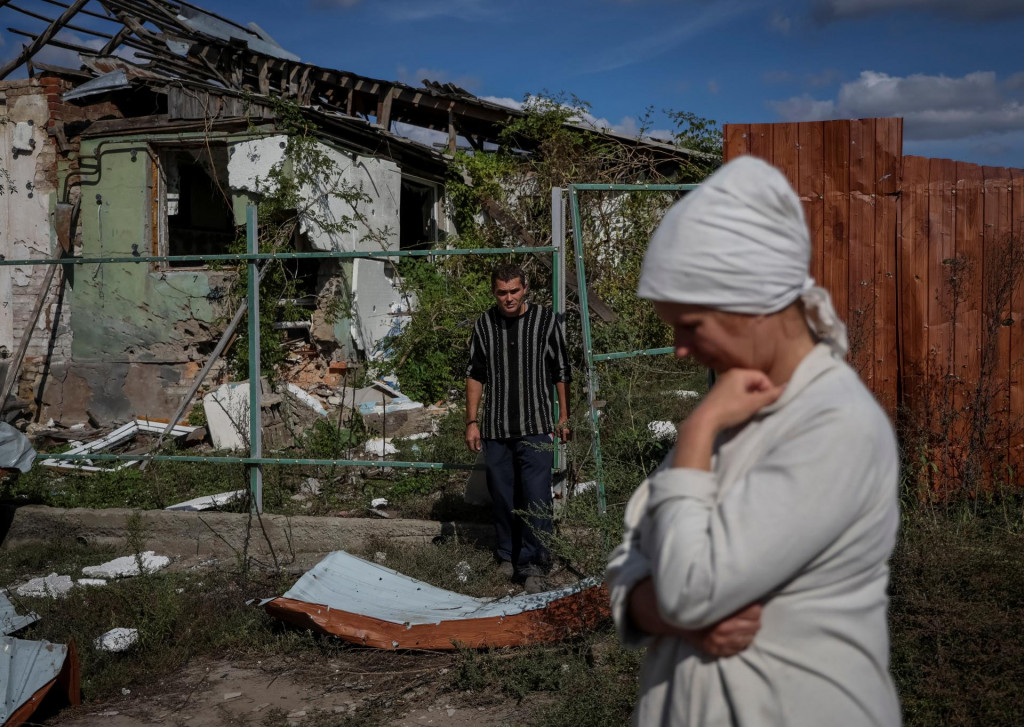 Obyvatelia Ukrajiny stoja pri ich zničenom dome. FOTO: Reuters