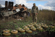 Ukrajinský vojak skúma protitankové míny v blízkosti zničeného ruského obrneného personálu (APC). FOTO: REUTERS