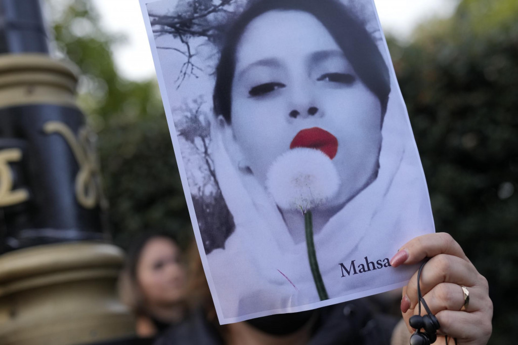 Demonštranti držia transparent s podobizňou 22-ročnej Iránky Mahsy Amíníovej pred iránskym veľvyslanectvom v Londýne v nedeľu 25. septembra 2022. FOTO: TASR/AP