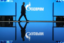 Muž kráča okolo loga ruského štátneho energetického giganta Gazprom, ilustračný obrázok. FOTO: TASR/AP

