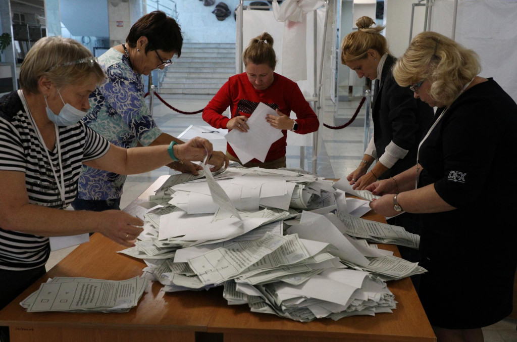 Členovia volebnej komisie sčítavajú hlasovacie lístky vo volebnej miestnosti na okupovanej Ukrajine. FOTO: REUTERS