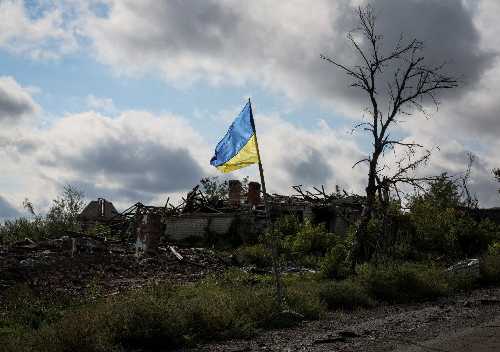 Ukrajinská štátna vlajka blízko zničených budov. FOTO: REUTERS