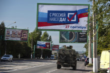 Vojenské vozidlo prechádza okolo bilbordu s nápisom ”S Ruskom navždy. FOTO: TASR/AP
