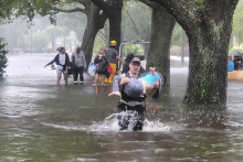 Hasiči pomáhajú ľuďom do bezpečia na zaplavenej ulici v meste Orange County na Floride. FOTO: TASR/AP