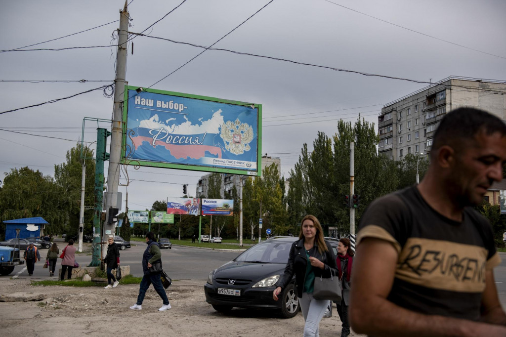 Ľudia kráčajú okolo bilbordu s nápisom ”Naša voľba - Rusko”. FOTO: TASR/AP