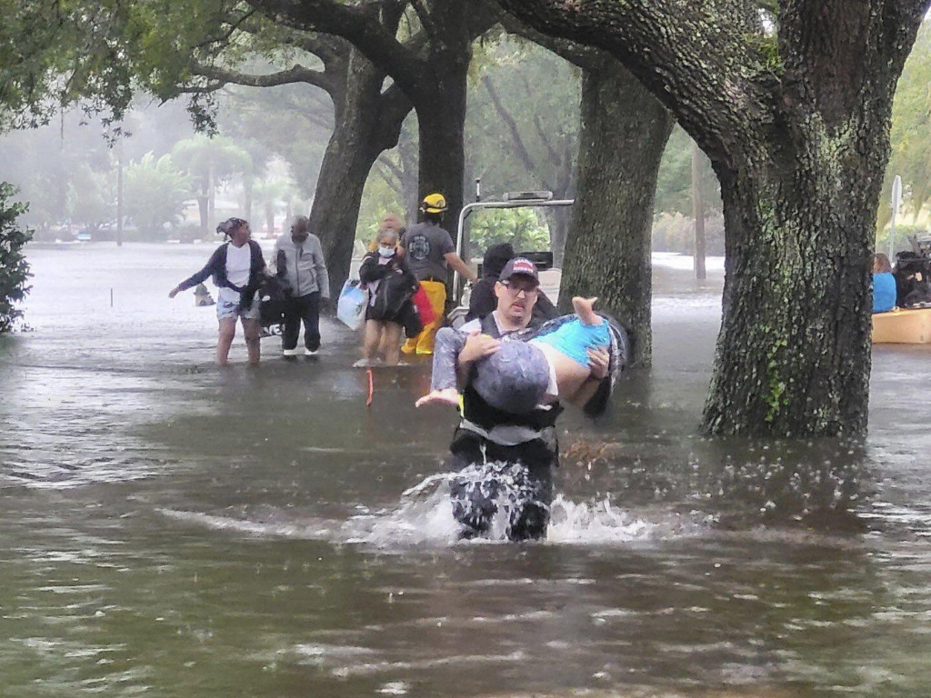 Hasiči pomáhajú ľuďom do bezpečia na zaplavenej ulici v meste Orange County na Floride. FOTO: TASR/AP