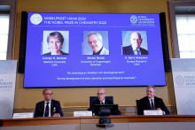 Fotografie laureátov Nobelovej ceny za chémiu Caroline R. Bertozziová, Morten Meldal a K. Barry Sharpless na obrazovke.