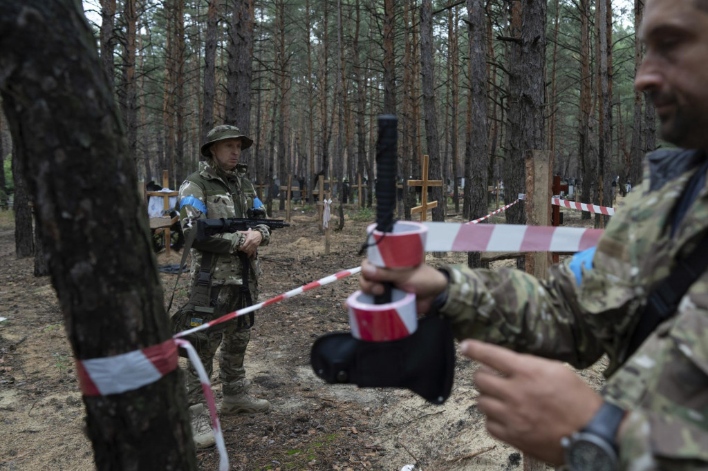 Vyšetrovanie neidentifikovaných hrobov civilistov a ukrajinských vojakov v meste Izium na východe Ukrajiny. FOTO: TASR/AP
