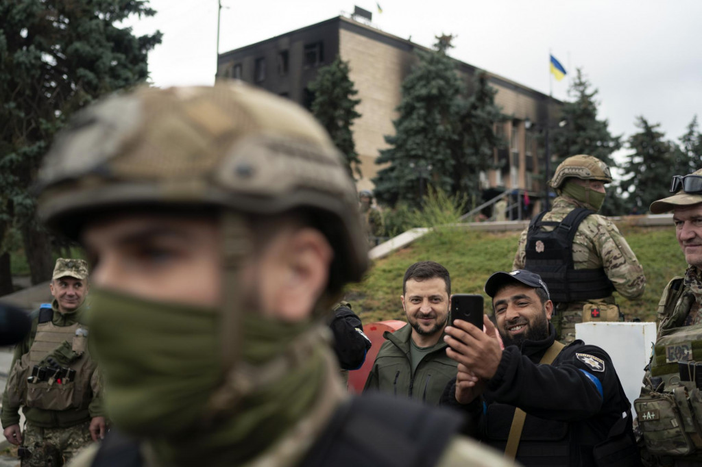 Ukrajinský prezident Volodymyr Zelenskyj (uprostred) sa fotí s policajtom počas návštevy mesta Izium v Charkovskej oblasti na východe Ukrajiny, ktoré ukrajinské sily nedávno oslobodili spod ruskej okupácie. FOTO: TASR/AP