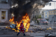 Zdravotník uteká okolo horiaceho auta po ruskom raketovom útoku v Kyjeve 10. októbra.