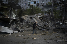 Zamestnanec upratuje pred predajňou s autami, ktorú zničil ruský raketový útok v meste Záporožie.
