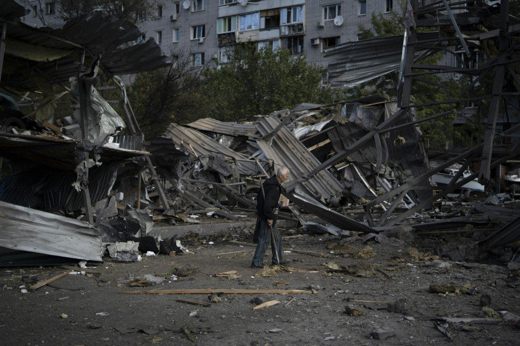 Zamestnanec upratuje pred predajňou s autami, ktorú zničil ruský raketový útok v meste Záporožie.