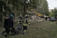 Ukrajinskí záchranári nesú vo vreci telo ženy po ruskom útoku v obci Mykolajivka. FOTO: TASR/AP