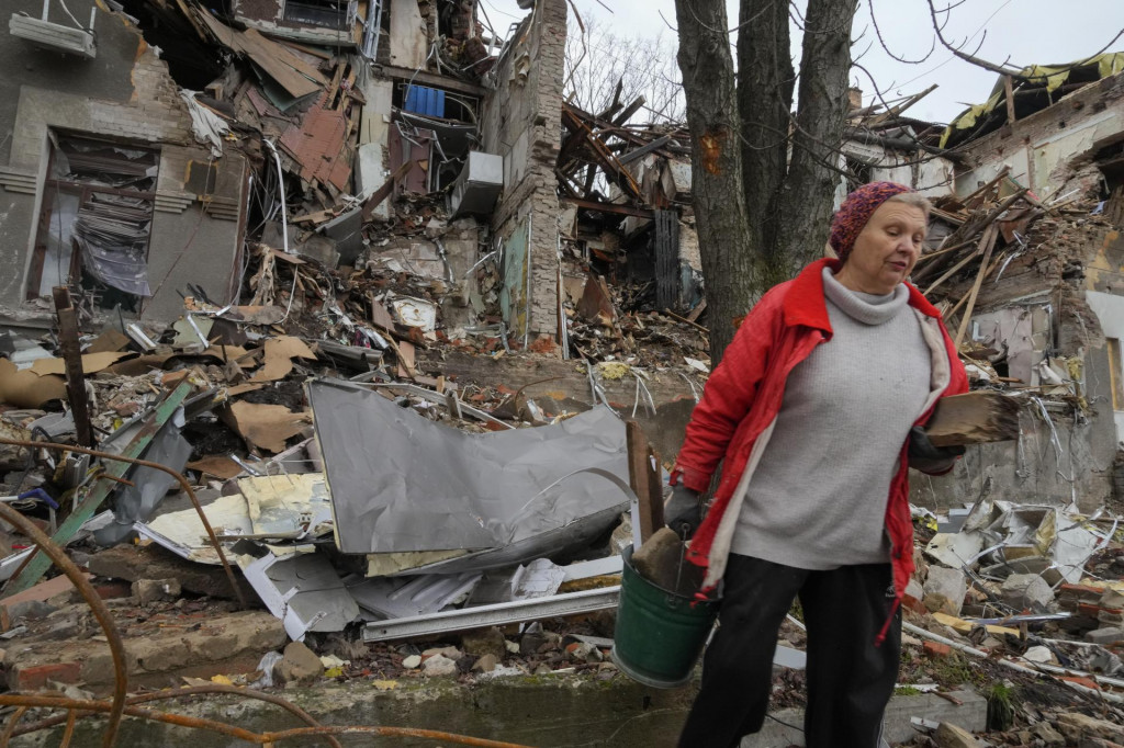 Miestna obyvateľka Nina nesie drevo k jej zničenému domu po ruskom ostreľovaní. FOTO: TASR/AP