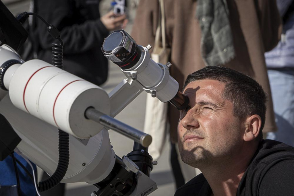 Muž sleduje cez teleskop čiastočné zatmenie Slnka. FOTO: TASR/AP