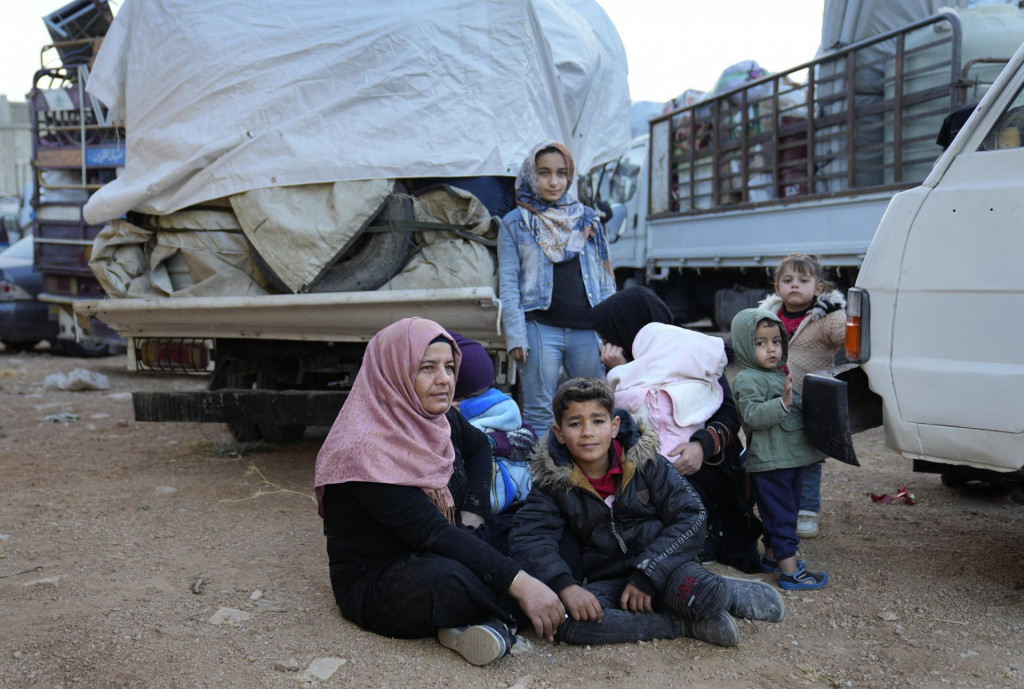 Rodina sýrskych utečencov sedí na zemi a čaká na zhromažďovacom stanovisku. FOTO: TASR/AP