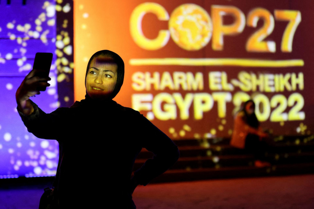 FILE PHOTO: A woman takes a selfie in front of a wall lit with the sign of COP27, as the COP27 climate summit takes place, at the Green Zone in Sharm el-Sheikh, Egypt November 10, 2022. REUTERS/Mohamed Abd El Ghany/File Photo SNÍMKA: Mohamed Abd El Ghany