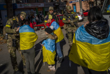 Príslušník ukrajinských obranných síl podpisuje ukrajinskú vlajku obyvateľom v oslobodenom meste Cherson na juhu Ukrajiny. FOTO: TASR/AP