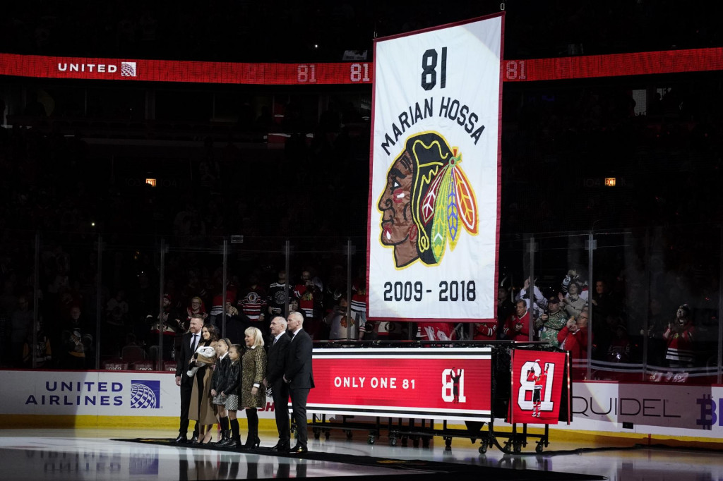 Mari&aacute;n Hossa (vľavo) so svojou rodinou p&oacute;zuje počas vyvesenia jeho dresu pred hokejov&yacute;m z&aacute;pasom z&aacute;morskej NHL medzi Chicagom Blackhawks a Pittsburghom Penguins. FOTO: TASR/AP