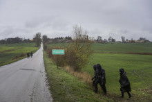 Policajti prezerajú pole pred poľnohospodárskym objektom v poľskej obci Przewodów, ktorú zasiahla raketa. FOTO: TASR/AP

