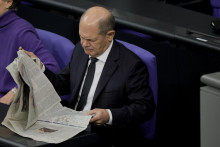 Nemecký kancelár Olaf Scholz si číta noviny počas rozpravy o štátnom rozpočte na rok 2023 na zasadnutí parlamentu v Berlíne. FOTO: TASR/AP