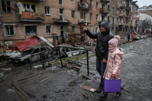 Miestni obyvatelia kráčajú v blízkosti obytného domu zničeného ruským raketovým útokom v meste Vyšhorod neďaleko Kyjeva. FOTO: REUTERS