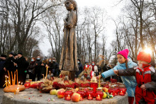 Deti kladú klasy pšenice na pamätník v Kyjeve, ktorý je venovaný obetiam hladomoru, rok 2020. FOTO: REUTERS