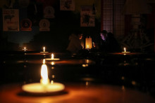 Ľudia v podniku vo Ľvove sedia pri sviečkach po tom, ako ruský útok viedol k výpadku elektriny. FOTO: REUTERS