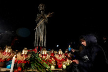 Žena zapaľuje sviečku pri pamätníku v Kyjeve, ktorý je venovaný obetiam hladomoru. FOTO: Reuters